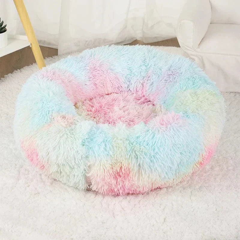 Fluffy pastel-colored calming bed for pets on a soft rug.