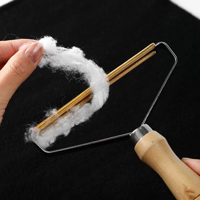 Wood-handled lint remover with copper blades removing pet hair from fabric.